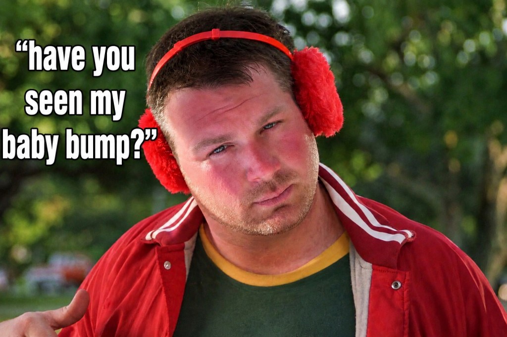 A man wearing red earmuffs and a red jacket, with a serious expression, asking, 'have you seen my baby bump?'