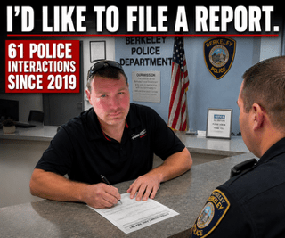 A man sitting at a desk in a police station filling out a report, facing a police officer. Text overlay reads 'I'D LIKE TO FILE A REPORT' and '61 POLICE INTERACTIONS SINCE 2019'.
